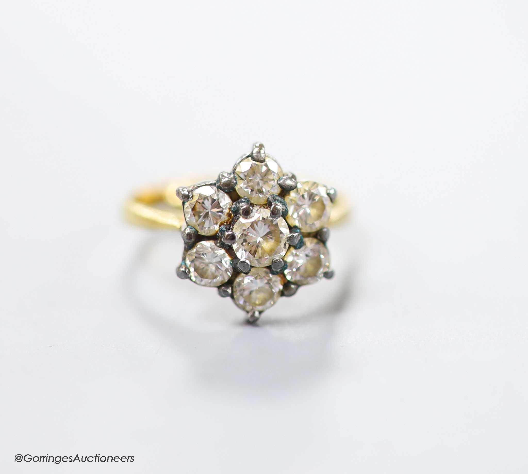 A modern 18ct gold and seven stone diamond cluster ring, size E (sizing spheres), gross weight 3.7 grams.